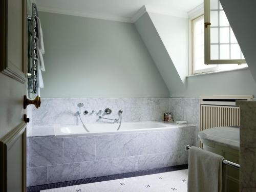 a bathroom with a bath tub and a sink at Schlosshotel Kronberg - Hotel Frankfurt in Kronberg im Taunus