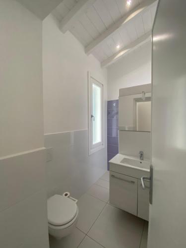 a white bathroom with a toilet and a sink at villetta sul mare Rachele in Marina di Campo
