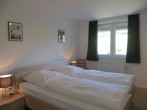a bedroom with a white bed with a window at Ferienwohnungen Grafenfelder Hof in Gerolstein