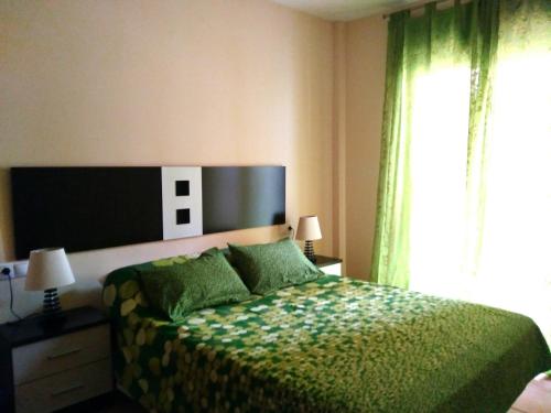 une chambre avec un lit avec un couvre-lit vert et une fenêtre dans l'établissement Villa Juan, à L'Eucaliptus