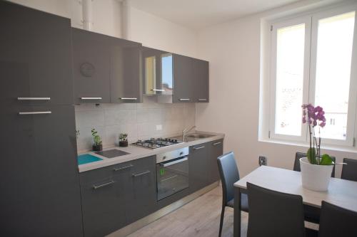 a kitchen with gray cabinets and a table with a dining room at Veronese 4 in Trieste