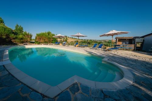 einen Pool neben einem Strand mit Sonnenschirmen in der Unterkunft Colle Regnano in Tolentino