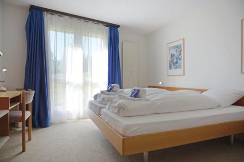 a bedroom with a large bed with blue curtains at Apartment Enzian mit Mitbenutzung SPA & Wellness - GRIWA RENT AG in Beatenberg