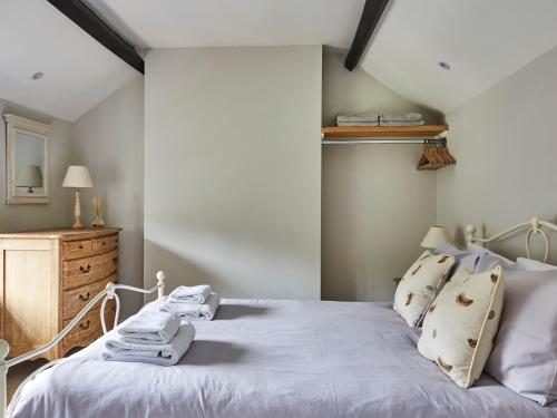 a bedroom with a white bed and a wooden dresser at Lilly Cottage in Lydney
