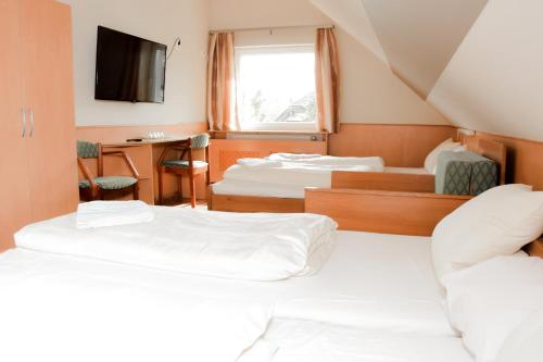 um quarto com 3 camas, uma secretária e uma televisão em Csikar Csárda és Panzió em Kőszeg