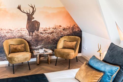 a room with two chairs and a painting of a deer at de Vogelensangh in Vogelenzang