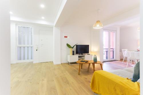a white living room with a couch and a tv at Cosy Guesthouse - Sónias Houses in Lisbon