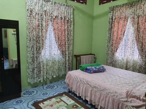 a bedroom with curtains and a bed and a mirror at Homestay Bonda in Kampong Amir