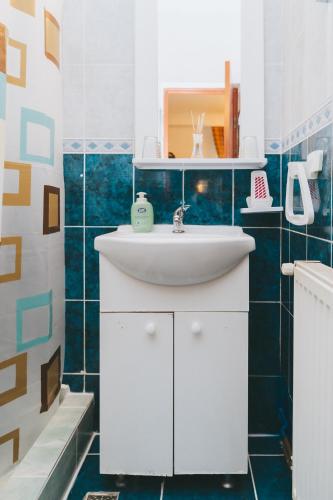 a bathroom with a white sink and blue tiles at Casa Vinco Vici in Turda