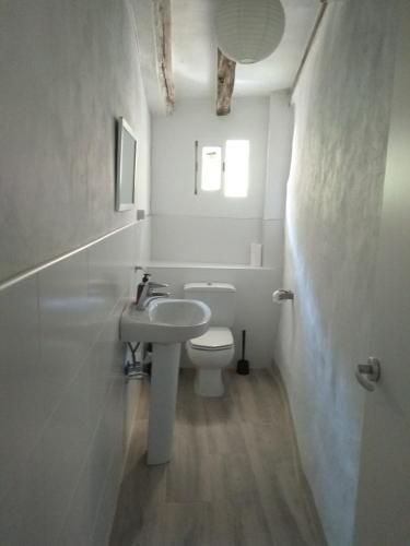 a white bathroom with a sink and a toilet at Casa Flor de lis in Herce