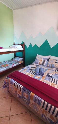 a bedroom with two beds with a mountain mural on the wall at Suítes Pouso do Sol in Praia de Araçatiba