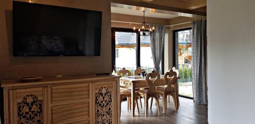a dining room with a table with chairs and a flat screen tv at Domek Melania in Zakopane