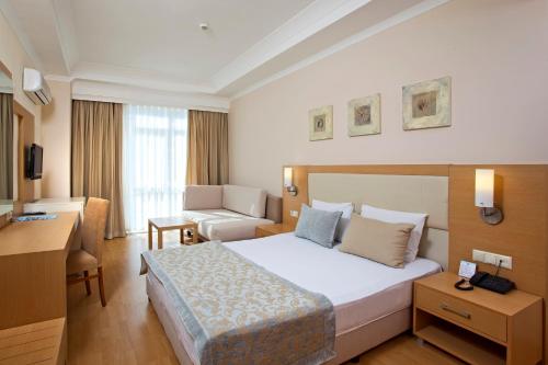 コナクリにあるTitan Select Hotel Ultra All Inclusiveのベッドとデスクが備わるホテルルームです。