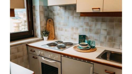 een keuken met een fornuis bovenoven naast een gootsteen bij Apartment Veldener Bucht by Seebnb in Velden am Wörthersee