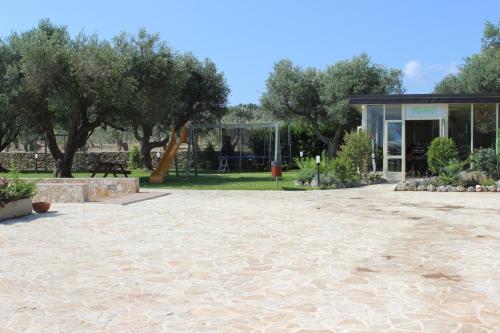 a park with a building and trees in the background at Masseria Un Posto al Sole in Otranto