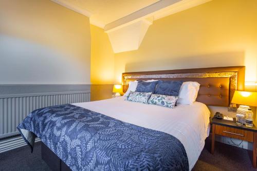 a bedroom with a large bed with blue and white sheets at The White Hart Hotel, Boston, Lincolnshire - The Coaching Inn Group in Boston