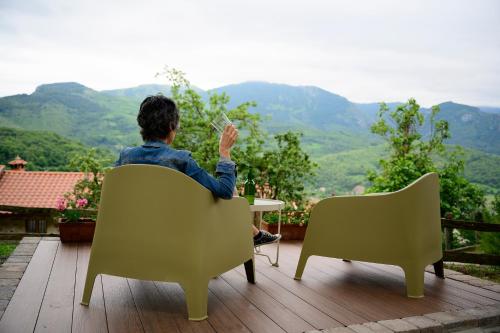 a man sitting in a chair looking at the mountains at La Xamoca Apartamentos Rurales in Campiellos