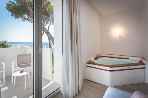 Zimmer mit Badewanne und Fenster in der Unterkunft The Sense Experience Resort in Follonica