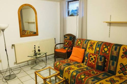 a living room with a couch and a table and a mirror at Biete ruhige Zwei-Zimmer Souterrain-Wohnung in Niederkassel