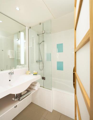 a bathroom with a sink and a shower at Novotel Manchester West in Worsley