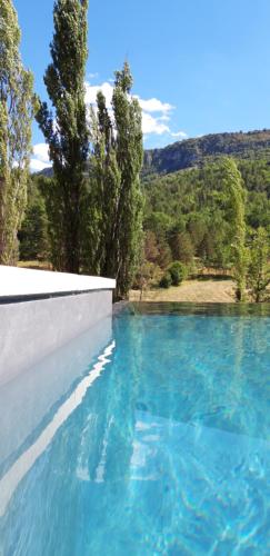 un bassin d'eau bleue avec des arbres en arrière-plan dans l'établissement Gîtes Les Costoliers, à Châteauneuf-Miravail