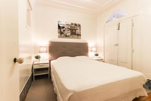 um pequeno quarto com uma cama branca e uma secretária em Belem Prestige by Homing em Lisboa