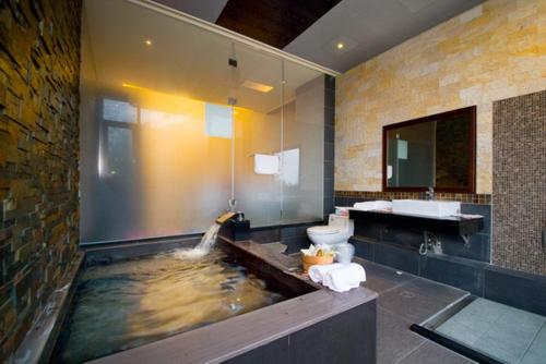 a bathroom with a pond with a toilet and a sink at 礁溪景觀溫泉會館 in Jiaoxi