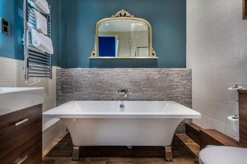 a bathroom with a white tub and a mirror at The White Hart Hotel, Boston, Lincolnshire - The Coaching Inn Group in Boston