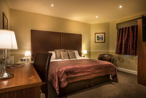 a hotel room with a bed with a desk and a bed sidx sidx sidx sidx at The White Hart Hotel, Boston, Lincolnshire - The Coaching Inn Group in Boston