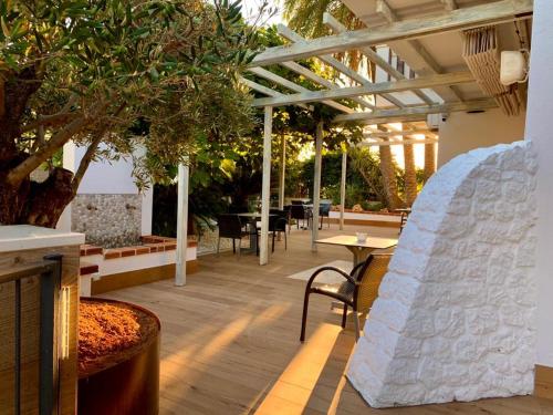 a covered patio with tables and chairs and a tree at Lux Isla in Talamanca
