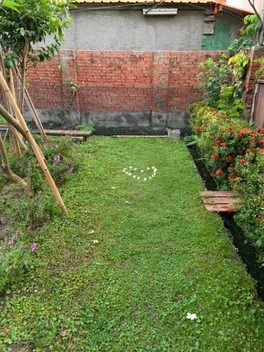 a garden with a lawn with flowers and a brick wall at A Day in Lukang Homestay in Lugang