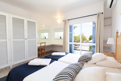 two beds in a room with a large window at Windmill Hill in Albufeira
