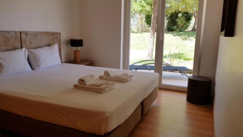 a bedroom with a bed with two towels on it at T2 Cabanas Gardens piscina e praia in Cabanas de Tavira