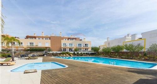 une image d'une piscine en face d'un bâtiment dans l'établissement T2 Cabanas Gardens piscina e praia, à Cabanas de Tavira