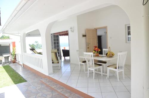 a white dining room with a white table and chairs at Ixora Villa in Anse Royale