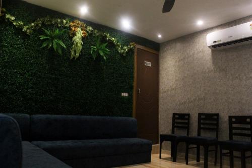a room with a green wall with a couch and chairs at Perfectstayz Premium Ganga Heights at Harkipauri Road in Haridwār