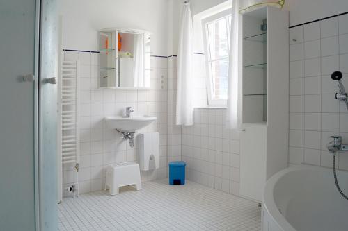 a white bathroom with a sink and a bath tub at Bontemps Apartment in Timmendorfer Strand