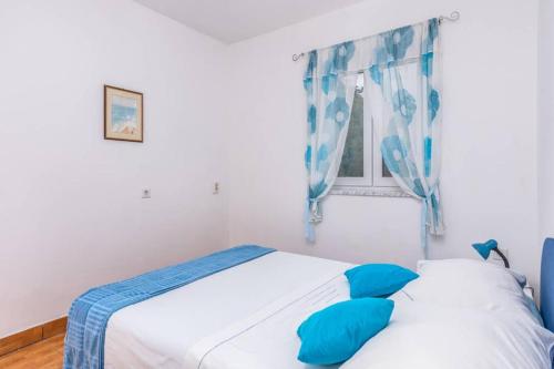 Schlafzimmer mit einem Bett und einem Fenster mit blauen Kissen in der Unterkunft Apartment Mira 3 in Klimno