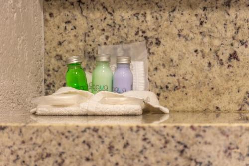three bottles of soap and a pair of towels on a counter at Hotel Flamingo Inn in Querétaro