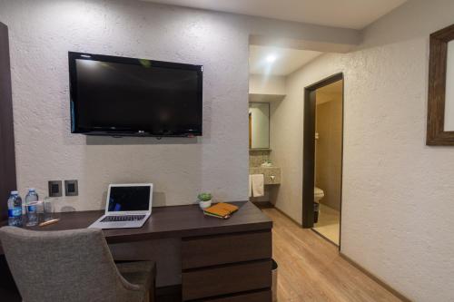 a room with a desk with a laptop and a television at Hotel Flamingo Inn in Querétaro