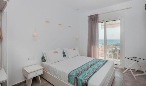 a white bedroom with a bed and a large window at Mr & Mrs K Bianco in Potos