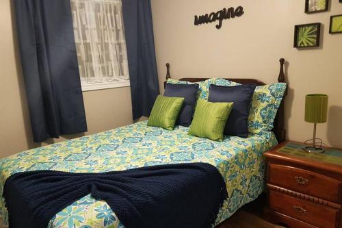 a bedroom with a bed with blue and green pillows at Sarnia's Hidden Gem - 3 BR/2 BA by College/Hwy/Arena in Sarnia