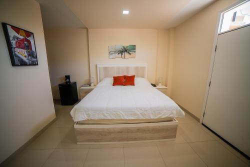 a bedroom with a white bed with a red pillow at California Comfort & Suites in Los Algodones