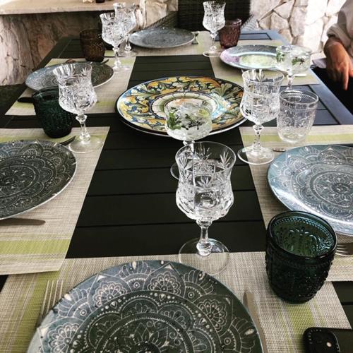 a table with plates and wine glasses on it at Villa Francesca - Manfredi Homes&Villas in Monte SantʼAngelo