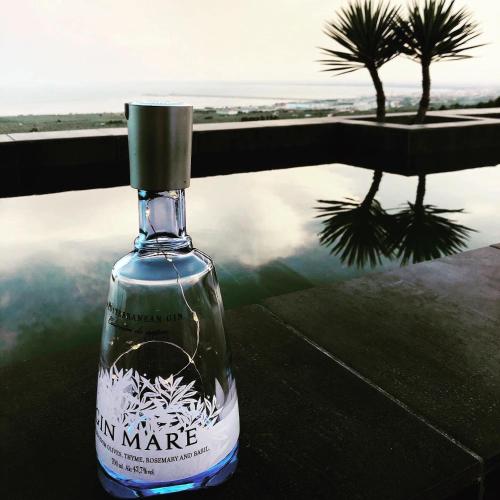 a bottle of wine sitting on a table with a reflection of a palm tree at Villa Francesca - Manfredi Homes&Villas in Monte SantʼAngelo