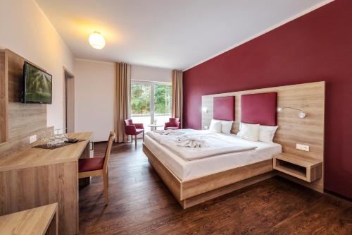 ein Hotelzimmer mit einem großen Bett und einem Schreibtisch in der Unterkunft Hotel zur Ostsee in Graal-Müritz