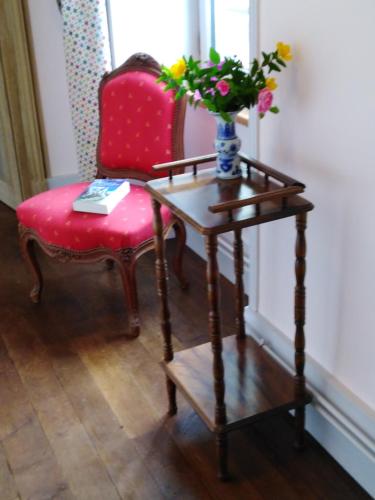 a table with a red chair and a vase with flowers on it at Chateau de Linard in Linard