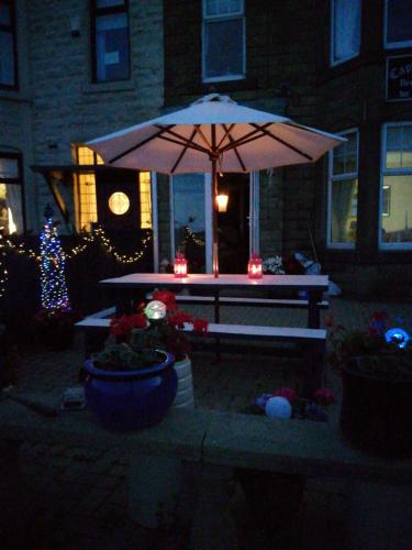 a picnic table with an umbrella in front of a house at Captains Lodge in Newbiggin-by-the-Sea