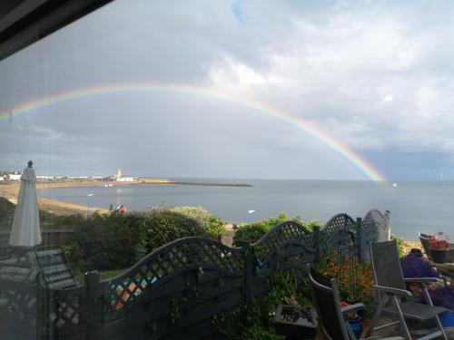 a rainbow over the ocean with chairs and a fence at Captains Lodge in Newbiggin-by-the-Sea
