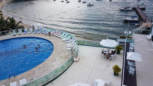 a swimming pool next to a body of water at Angra dos Reis, Angra Inn, Cantinho perfeito in Angra dos Reis